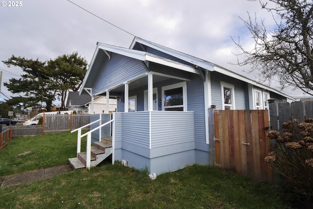 view of home's exterior featuring a porch, a yard, and fence