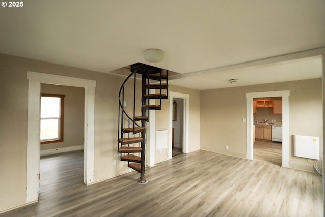 unfurnished living room with stairway, baseboards, and light wood-style floors