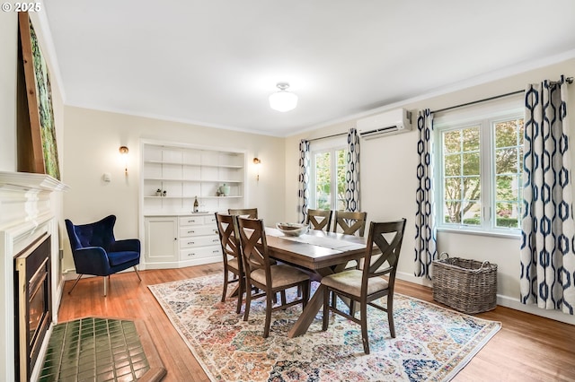 6209 SE 13th Ave, Portland, OR 97202 - dining area featuring a wall mounted AC, light wood-style floors, built in shelves, a glass covered fireplace, and ornamental molding