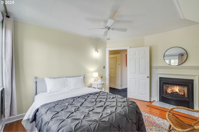6209 SE 13th Ave, Portland, OR 97202 - bedroom featuring wood finished floors, a glass covered fireplace, crown molding, ceiling fan, and baseboards