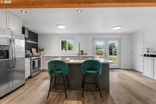 605 SE 104th Ave, Vancouver, WA 98664 - kitchen featuring appliances with stainless steel finishes, light countertops, light wood finished floors, french doors, and a kitchen breakfast bar