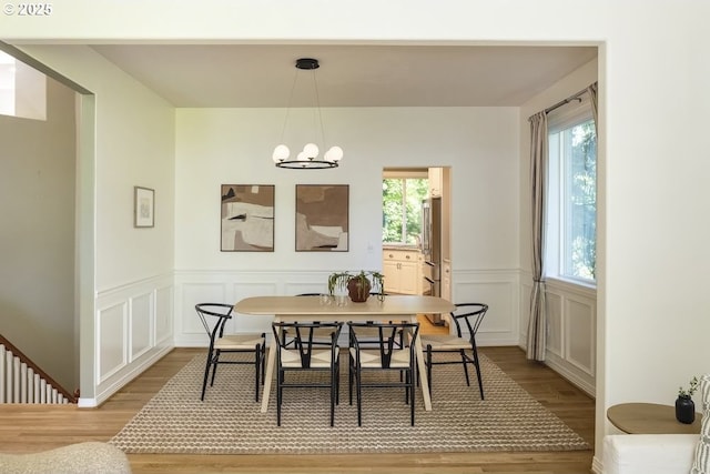 13037 SW Ascension Dr, Portland, OR 97223 - dining room with light wood finished floors, a chandelier, a wainscoted wall, and a decorative wall