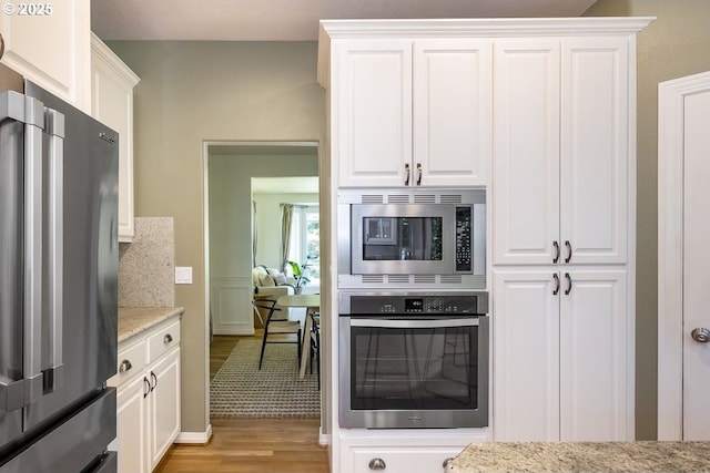 13037 SW Ascension Dr, Portland, OR 97223 - kitchen with appliances with stainless steel finishes, light wood-type flooring, white cabinets, light stone countertops, and backsplash