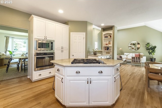 13037 SW Ascension Dr, Portland, OR 97223 - kitchen featuring appliances with stainless steel finishes, light wood finished floors, a kitchen island, white cabinetry, and recessed lighting