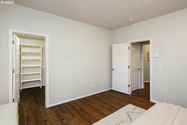 13037 SW Ascension Dr, Portland, OR 97223 - unfurnished bedroom featuring a walk in closet, wood finished floors, baseboards, and a closet