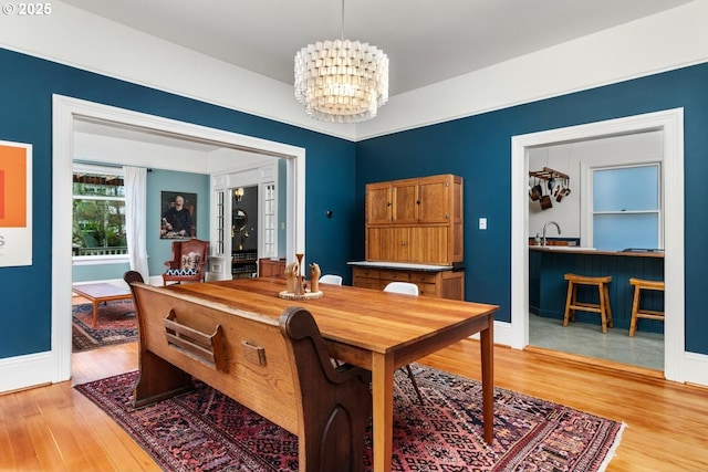 dining space featuring baseboards, light wood-style floors, and an inviting chandelier