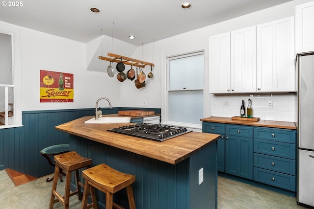 kitchen featuring wooden counters, blue cabinetry, a sink, white cabinets, and appliances with stainless steel finishes