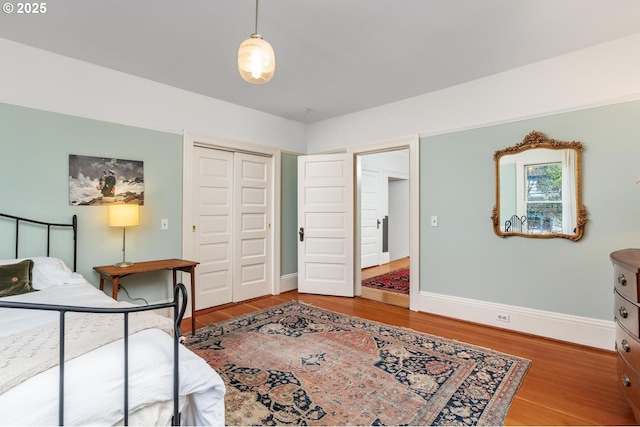 bedroom with a closet, baseboards, and wood finished floors