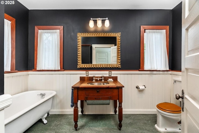 full bathroom featuring vanity, toilet, wainscoting, and a freestanding bath