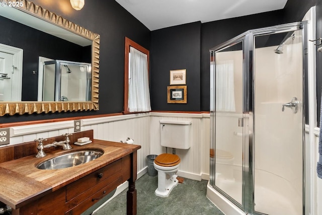 full bathroom with vanity, toilet, a stall shower, and wainscoting