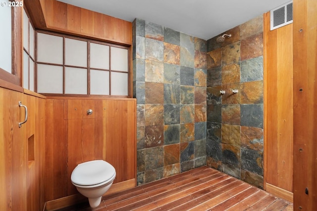 bathroom featuring visible vents, toilet, and tiled shower