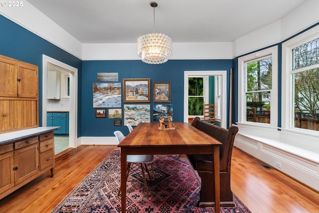 dining area with a notable chandelier, baseboards, light wood-style floors, and visible vents