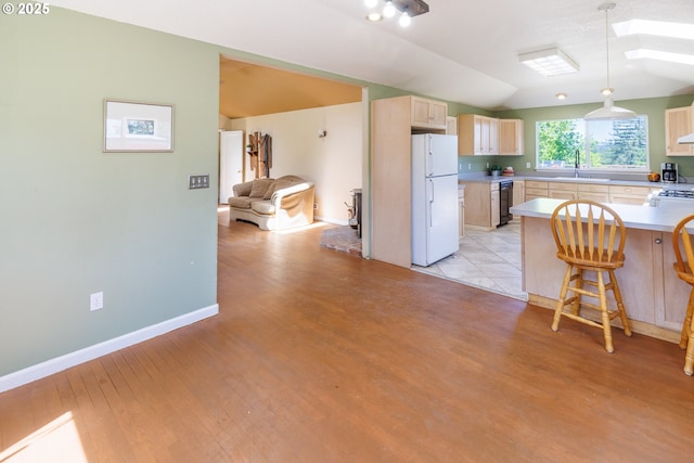 kitchen with freestanding refrigerator, light brown cabinetry, a sink, light wood-style flooring, and dishwasher