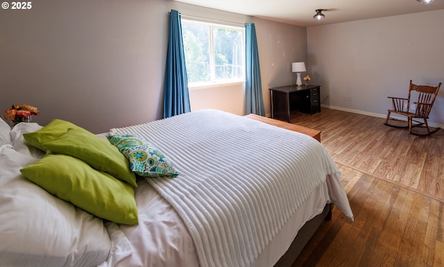 bedroom with wood-type flooring and baseboards