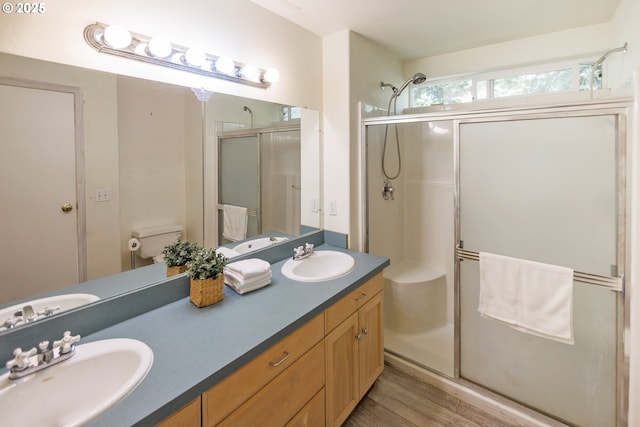 full bathroom with a stall shower, wood finished floors, double vanity, and toilet