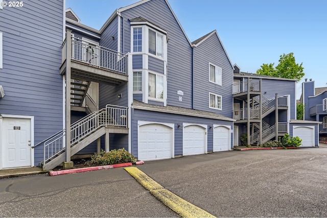 view of property with a garage, stairs, and driveway
