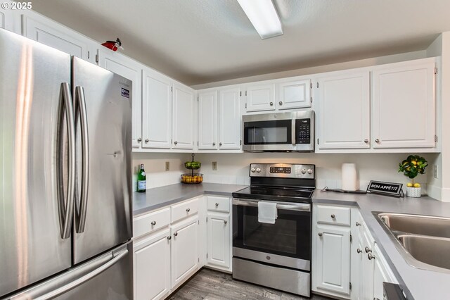 17532 NW Springville Rd Unit D8, Portland, OR 97229 - kitchen featuring stainless steel appliances, white cabinets, and wood finished floors