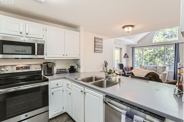 kitchen featuring appliances with stainless steel finishes, a sink, light countertops, white cabinets, and open floor plan