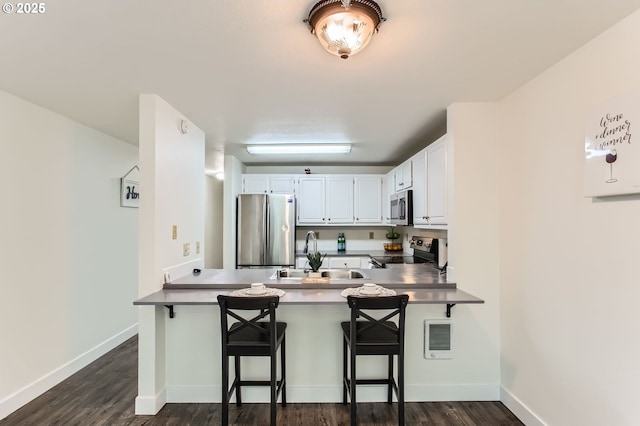 17532 NW Springville Rd Unit D8, Portland, OR 97229 - kitchen with appliances with stainless steel finishes, a peninsula, dark wood-style floors, and a breakfast bar area