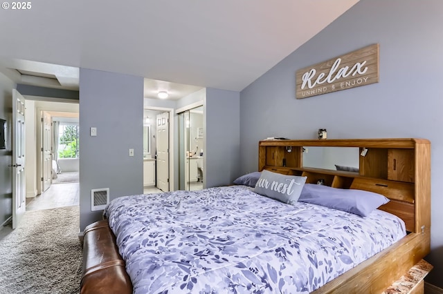 carpeted bedroom featuring a closet, baseboards, vaulted ceiling, and ensuite bath