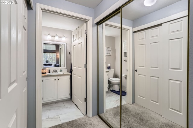 bathroom with toilet, marble finish floor, and vanity