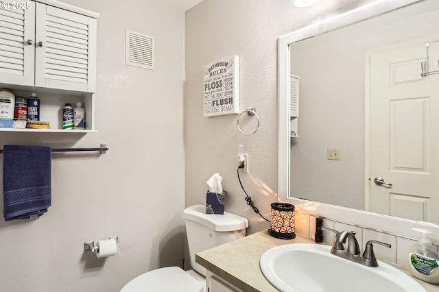 bathroom with toilet, visible vents, and vanity