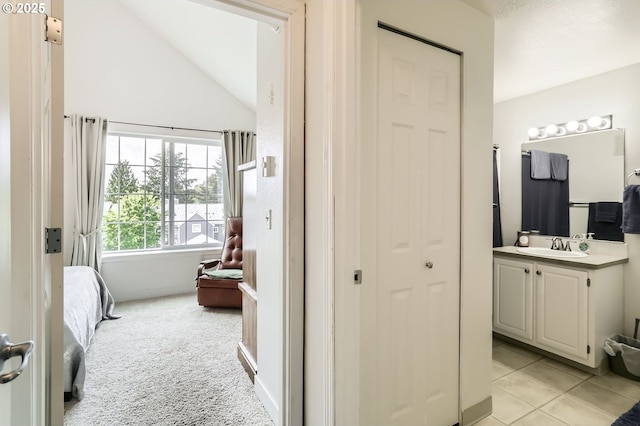 bathroom featuring vaulted ceiling, ensuite bathroom, tile patterned flooring, and vanity