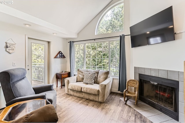 living area with wood-type flooring, high vaulted ceiling, baseboards, and a fireplace