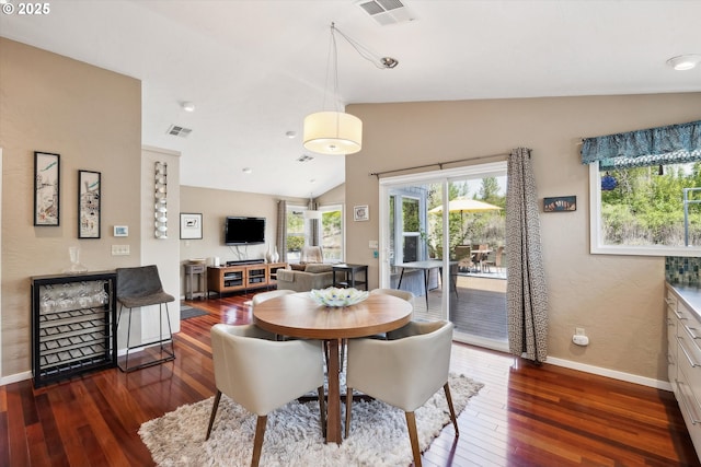 dining room with visible vents, lofted ceiling, and hardwood / wood-style flooring