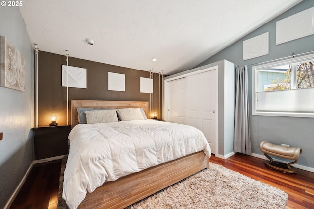 bedroom with a closet, baseboards, lofted ceiling, and wood finished floors