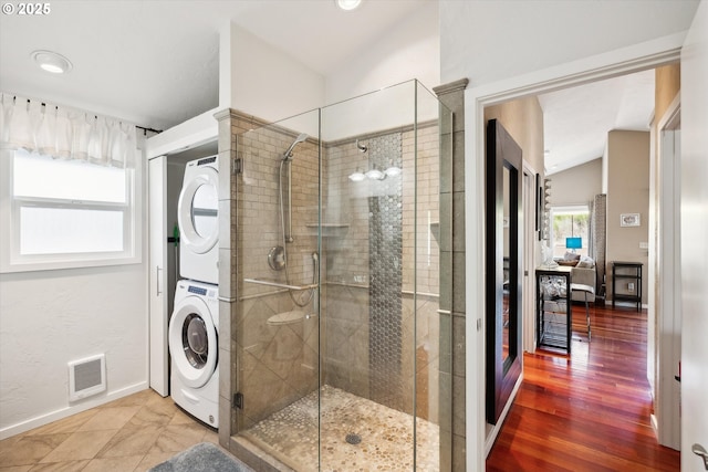 full bathroom featuring visible vents, stacked washer and clothes dryer, connected bathroom, and a shower stall