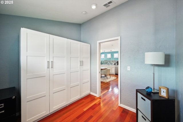 hall with baseboards, wood finished floors, and visible vents