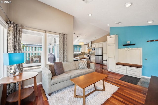 living area featuring plenty of natural light, dark wood-style flooring, lofted ceiling, and visible vents