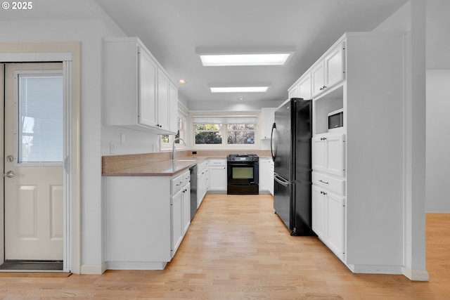 kitchen with white cabinetry, sink, black appliances, and light wood-type flooring