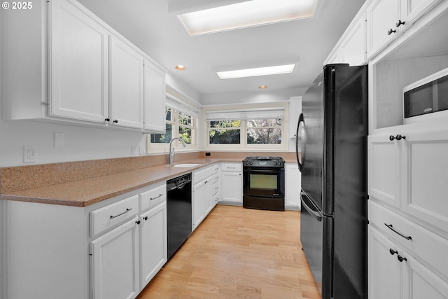 kitchen featuring white cabinets, sink, light hardwood / wood-style flooring, and black appliances