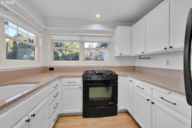 kitchen featuring sink, white cabinetry, light stone counters, light hardwood / wood-style floors, and black appliances