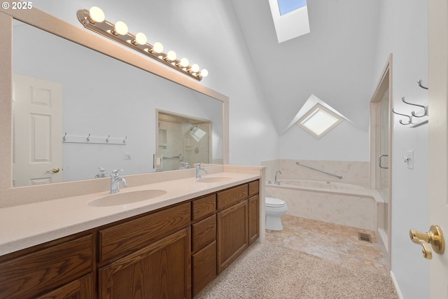 bathroom featuring vanity, toilet, a relaxing tiled tub, and a skylight