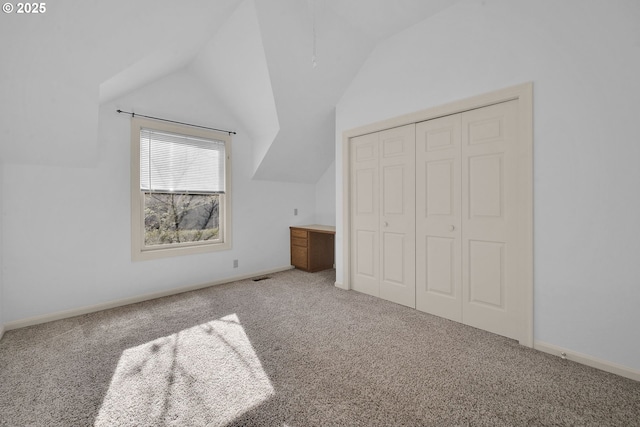 unfurnished bedroom with lofted ceiling, carpet floors, and a closet