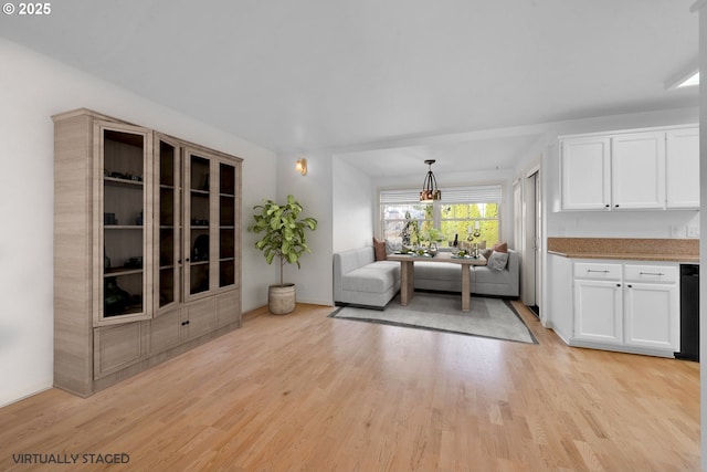 interior space with pendant lighting, light hardwood / wood-style floors, and white cabinets