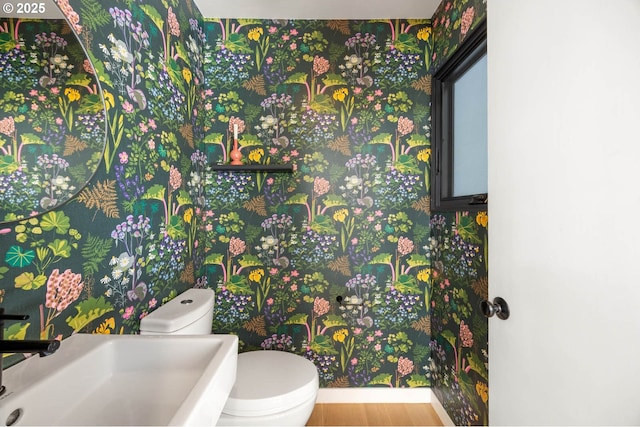2930 NW Quimby St, Portland, OR 97210 - half bath with toilet, a sink, baseboards, wood finished floors, and wallpapered walls