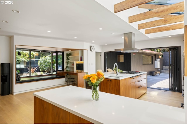 2930 NW Quimby St, Portland, OR 97210 - kitchen featuring a sink, light wood-style flooring, island exhaust hood, modern cabinets, and light countertops