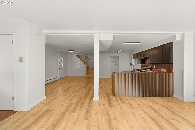 kitchen featuring light wood-style flooring, a sink, dark brown cabinetry, a baseboard heating unit, and open floor plan