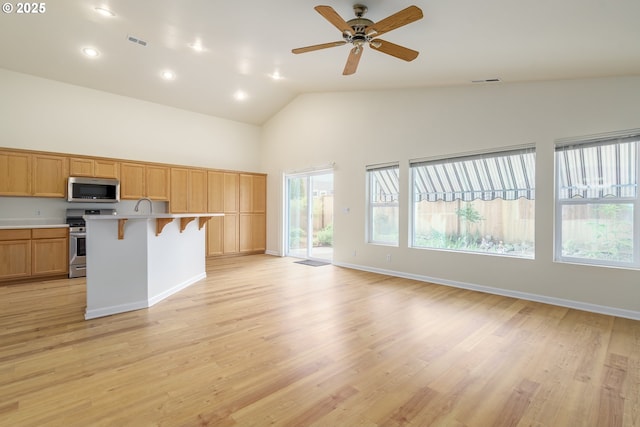 5470 Jeffrey Way, Eugene, OR 97402 - kitchen with stainless steel appliances, high vaulted ceiling, light countertops, a breakfast bar, and healthy amount of natural light