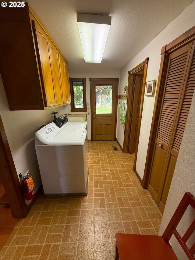 clothes washing area with cabinet space, washer and clothes dryer, and brick patterned floor