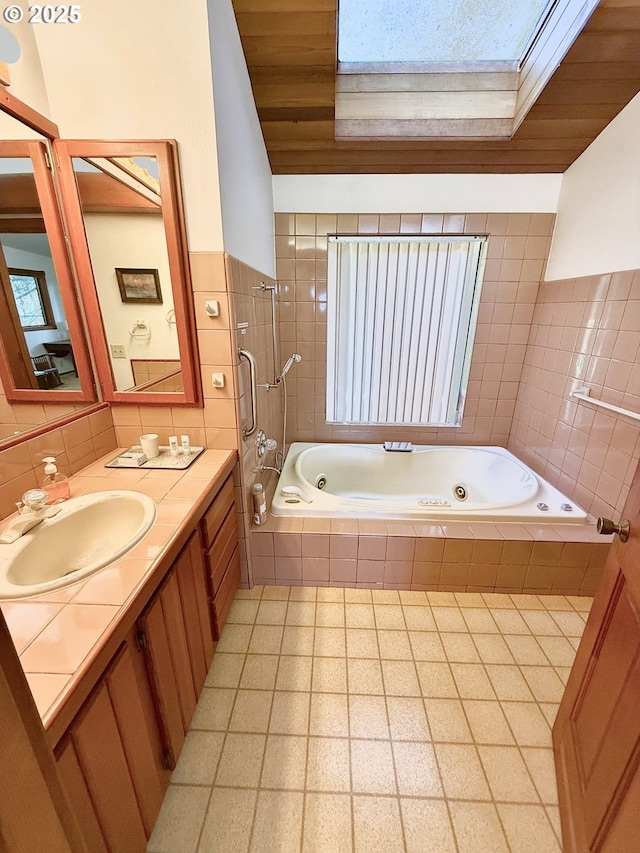 full bath featuring wood ceiling, a whirlpool tub, a skylight, tile walls, and vanity