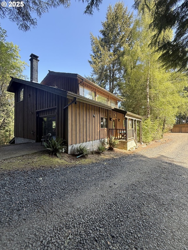 view of home's exterior with a chimney, board and batten siding, and a porch