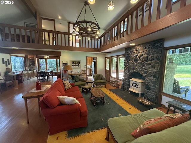 living area with a wood stove, a healthy amount of sunlight, high vaulted ceiling, and wood finished floors