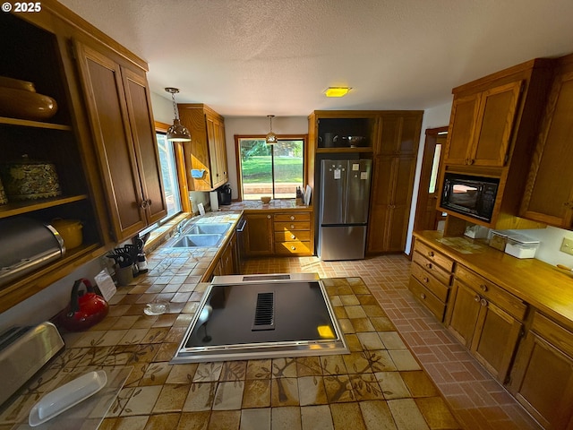 kitchen with freestanding refrigerator, tile countertops, a sink, black microwave, and open shelves
