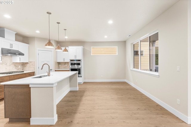 kitchen with backsplash, sink, an island with sink, and appliances with stainless steel finishes