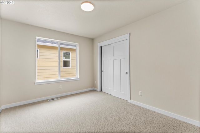 unfurnished bedroom with light carpet and a closet